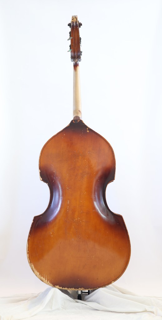 Back view of a vintage double bass showing the body and neck with some wear and tear.